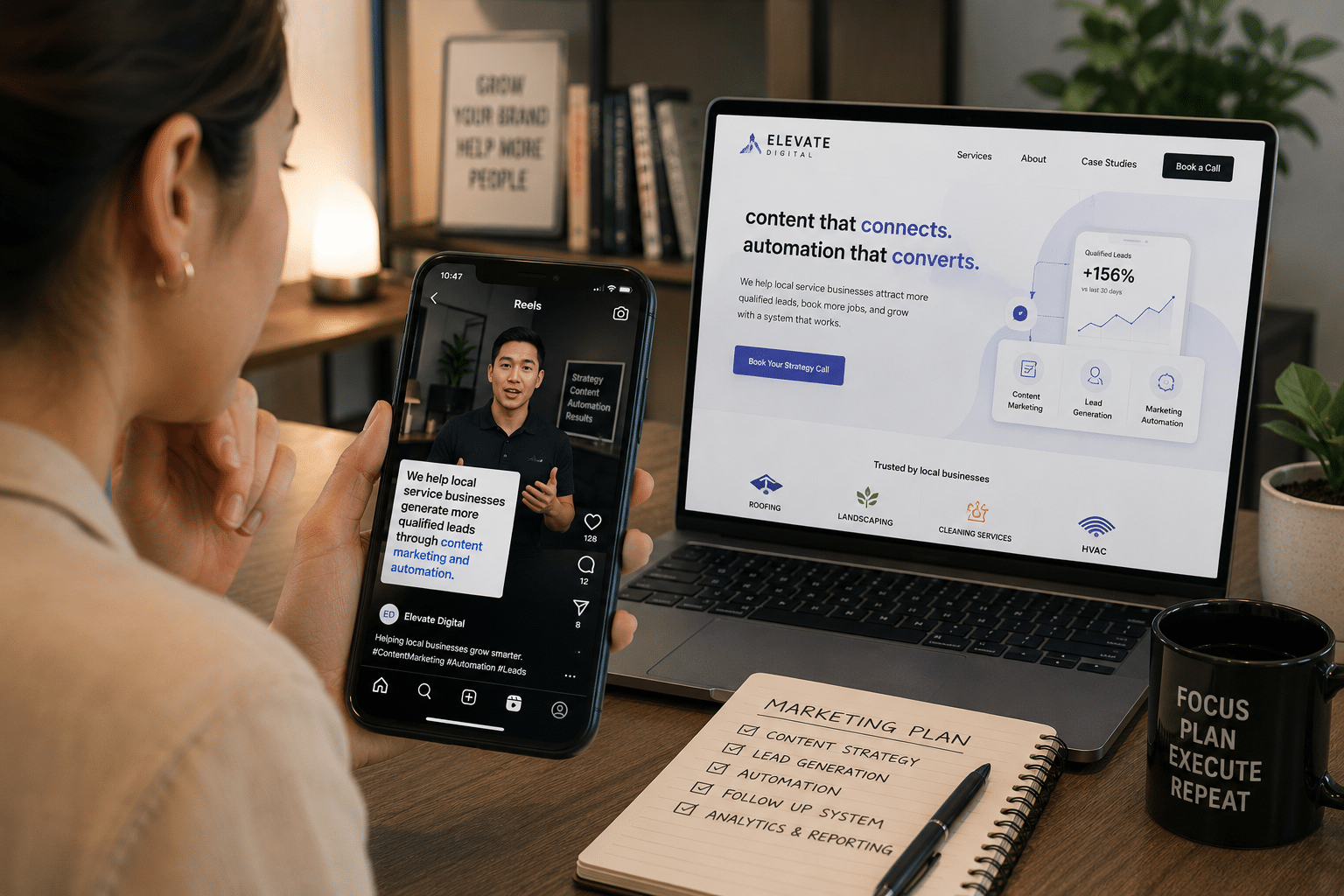 Person holds a smartphone playing a marketing reel while a laptop screen shows a marketing website for her small business in a home office setting.
